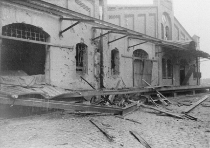 Bombentreffer. Stark beschädigter Hafenschuppen. Zerstörte Fenster und Tore, Splitter in den Wänden.